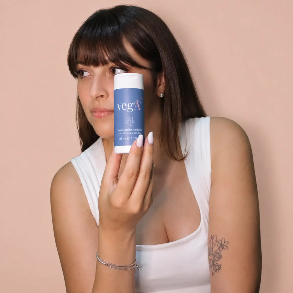 Ragazza con il tonico esfoliante vegA in mano accanto al viso