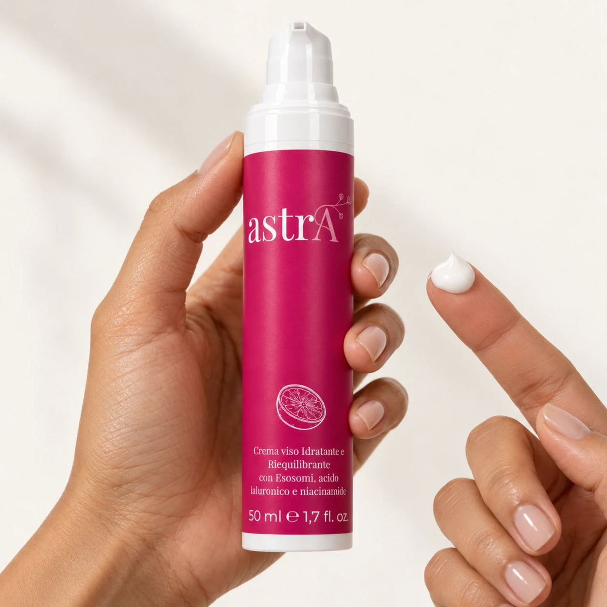 Mano che tiene la crema viso astrA e mostra un po' di crema sulla punta del dito