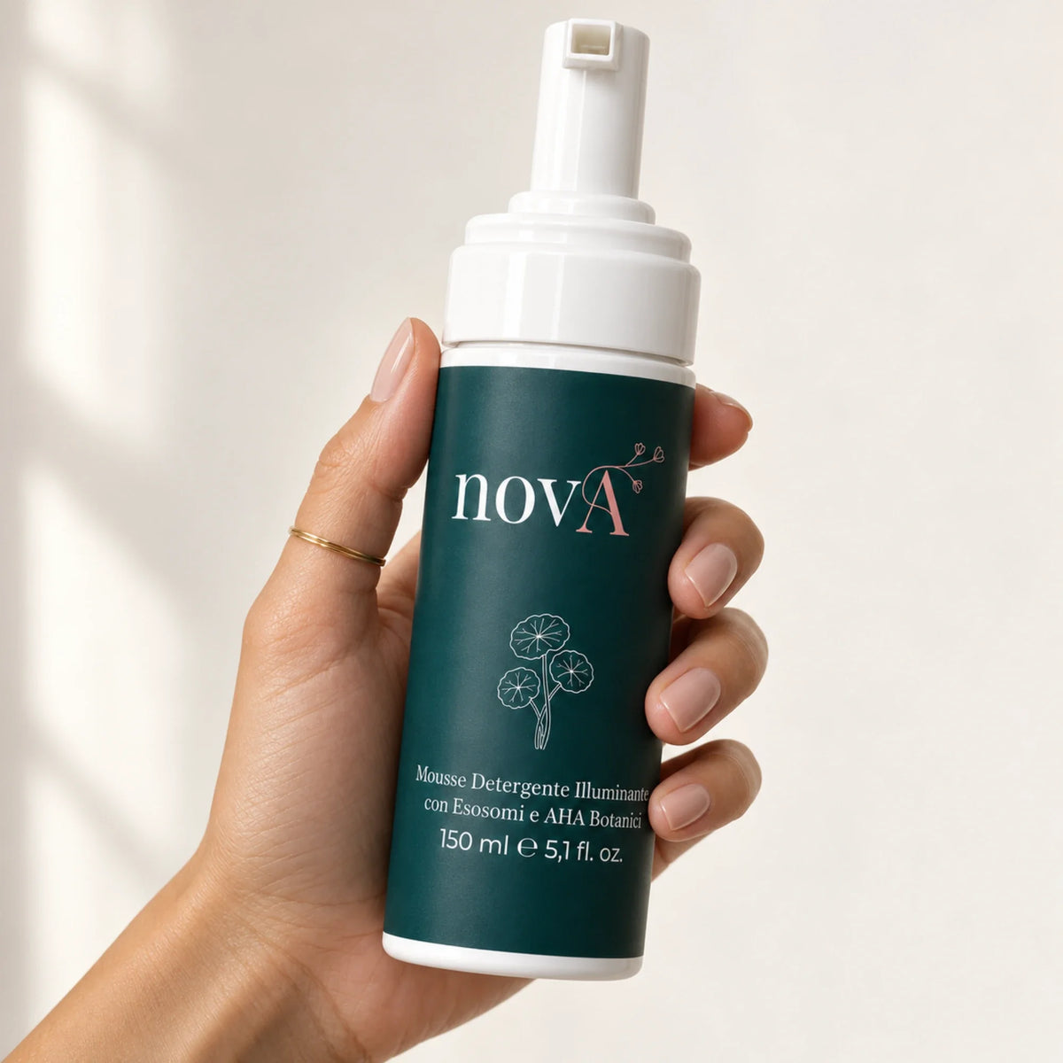 Mano che tiene il flacone della mousse detergente viso novA Curamour