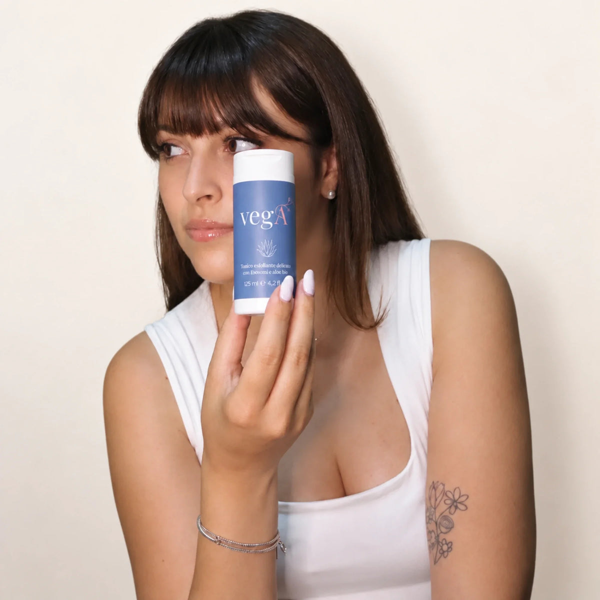 Donna con frangia che tiene il tonico esfoliante vegA vicino al viso